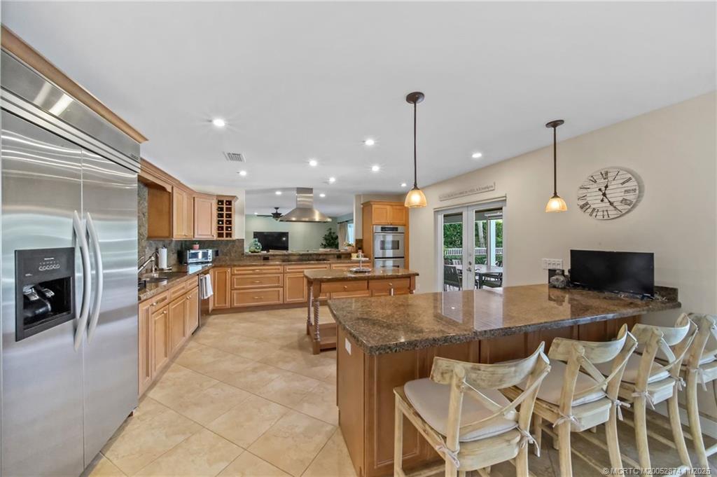 7 Island Road Stuart, FL 34996 - Photo 16 of 67 a kitchen with stainless steel appliances granite countertop a stove top oven a sink dishwasher a dining table and chairs with wooden floor