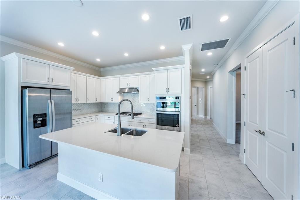 14756 Kingfisher Loop Naples, FL 34120 - Photo 3 of 16 a kitchen with stainless steel appliances kitchen island granite countertop a refrigerator and a sink