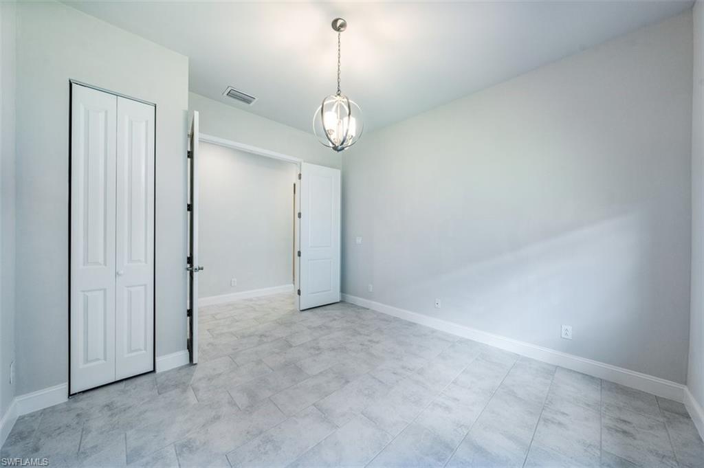 14756 Kingfisher Loop Naples, FL 34120 - Photo 9 of 16 an empty room with a chandelier fan and wooden floor