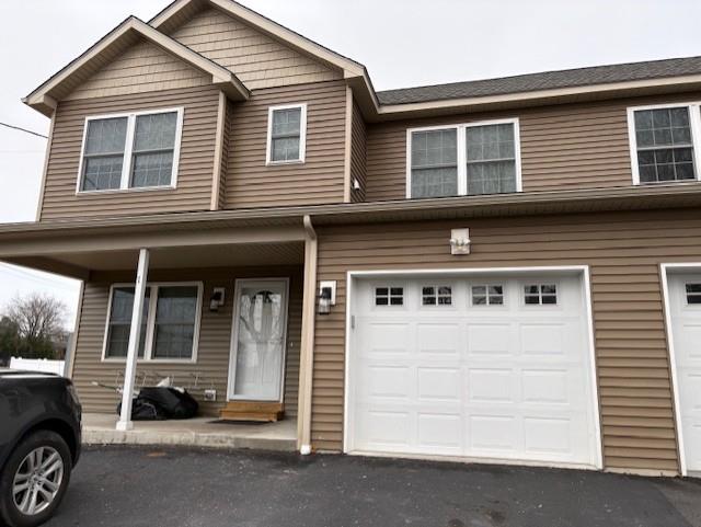 Townhome / multi-family property featuring aphalt driveway and a garage