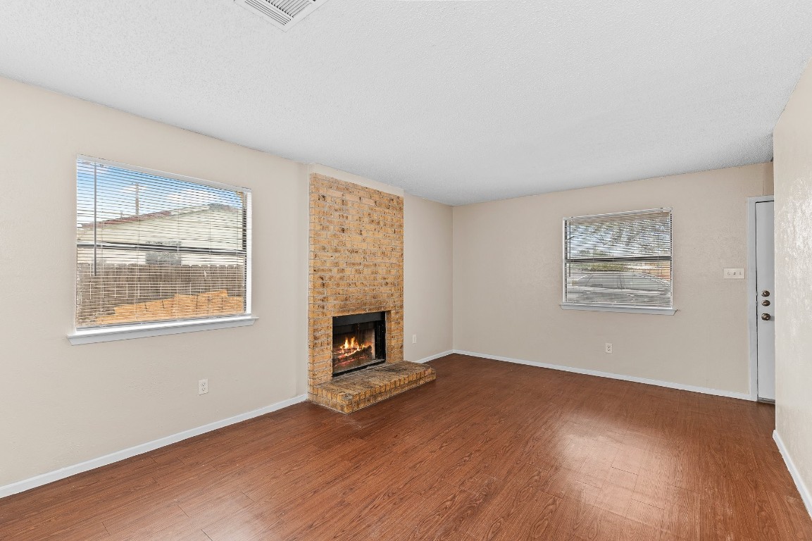 8412 Garcreek Circle, Unit D Austin, TX 78724 - Photo 5 of 23 an empty room with windows fireplace and wooden floor
