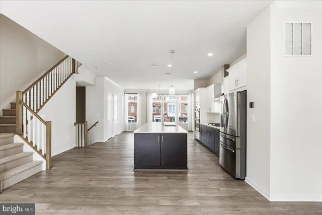 a view of a kitchen with refrigerator and wooden floor