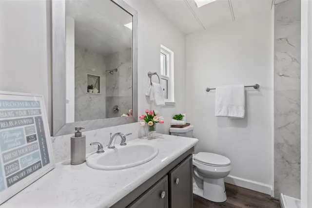 a bathroom with a granite countertop sink toilet and mirror