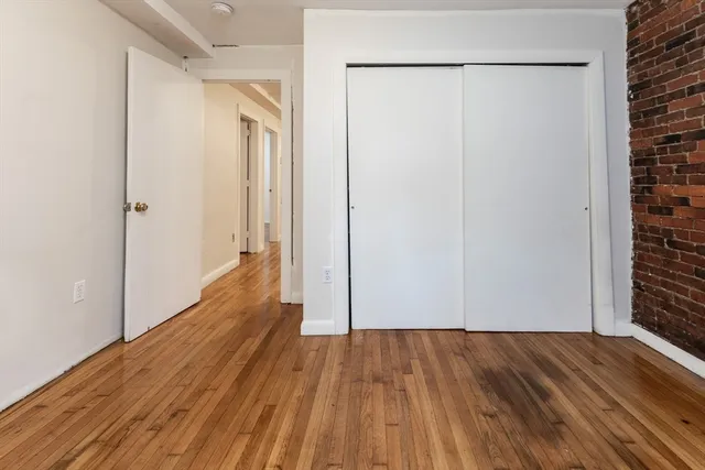 a view of a hallway with wooden floor and a bathroom