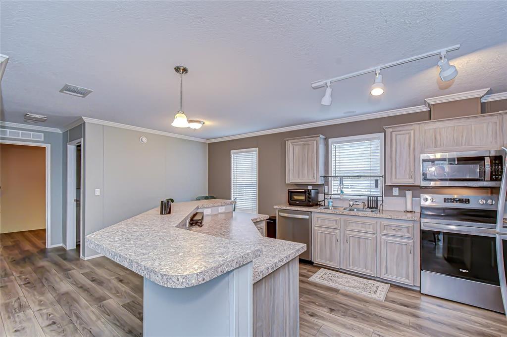 37749 Geiger Road Zephyrhills, FL 33542 - Photo 12 of 36 a kitchen with stainless steel appliances granite countertop a sink dishwasher a stove and a refrigerator with wooden floor