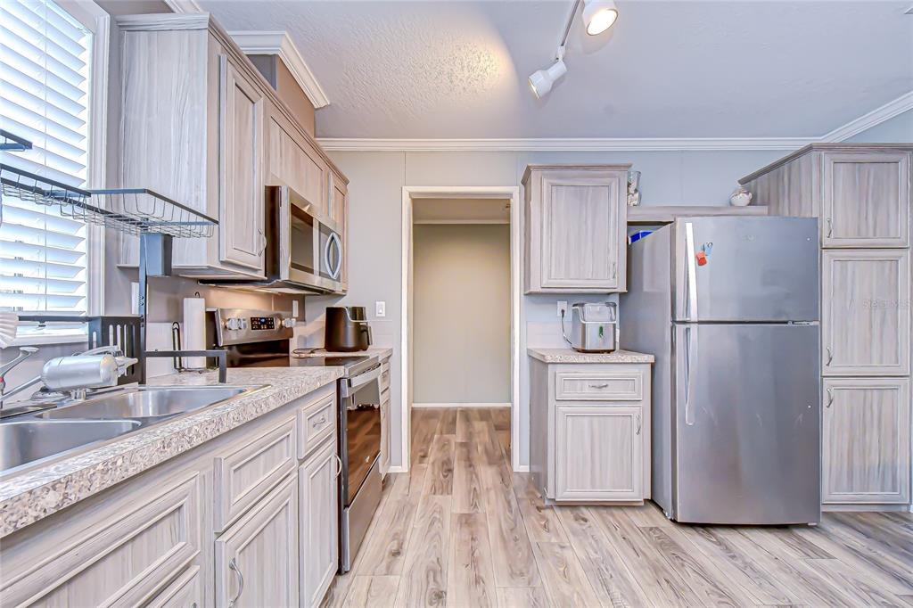 37749 Geiger Road Zephyrhills, FL 33542 - Photo 17 of 36 a kitchen with a refrigerator a stove top oven a sink and dishwasher with wooden floor