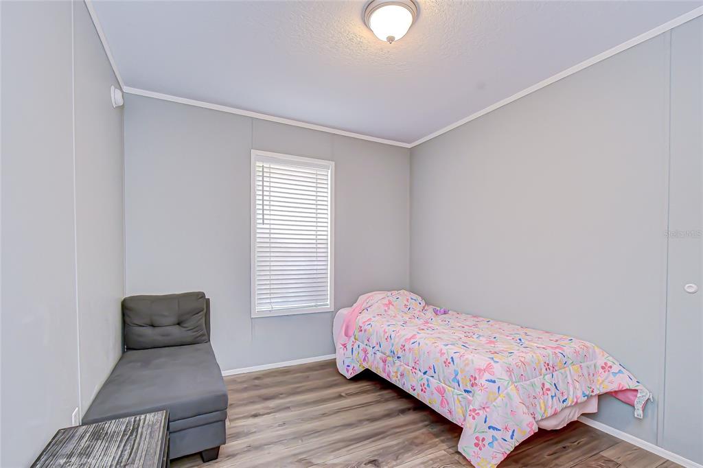 37749 Geiger Road Zephyrhills, FL 33542 - Photo 28 of 36 a bedroom with a bed and wooden floor