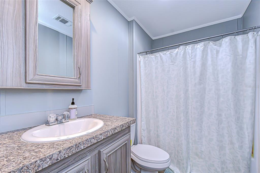 37749 Geiger Road Zephyrhills, FL 33542 - Photo 32 of 36 a bathroom with a granite countertop sink a toilet and a mirror