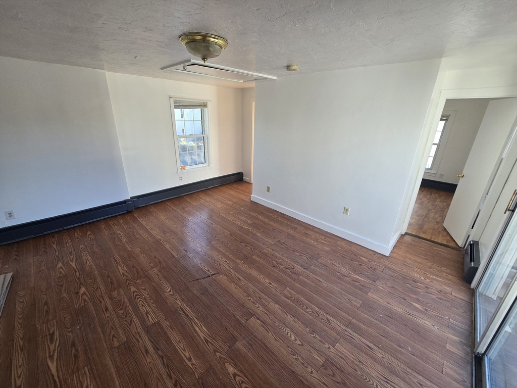 176 Green Street, Unit 2 Brockton, MA 02301 - Photo 2 of 15 a view of an empty room with wooden floor and a window