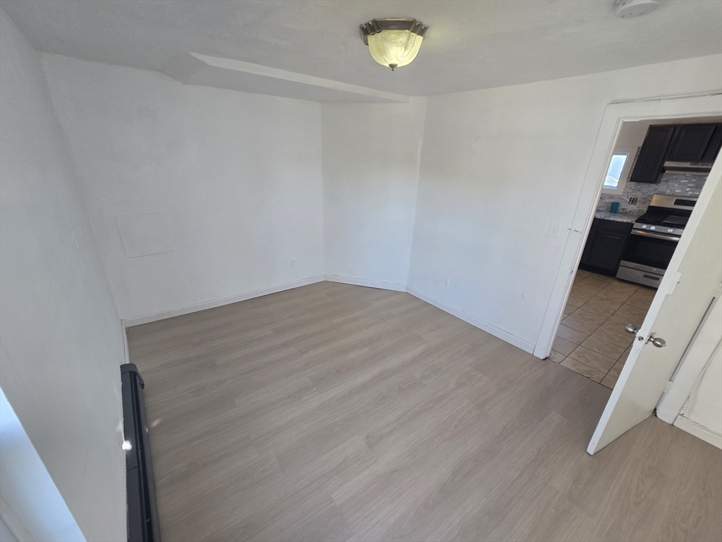 176 Green Street, Unit 2 Brockton, MA 02301 - Photo 4 of 15 an empty room with wooden floor