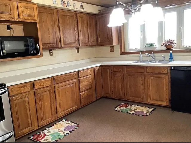 a kitchen with stainless steel appliances wooden cabinets a stove a sink and a microwave
