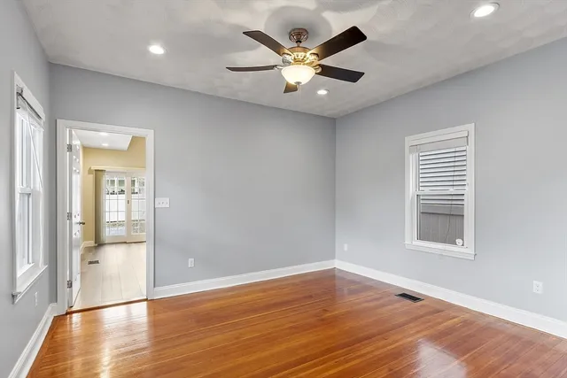 an empty room with wooden floor and a ceiling fan