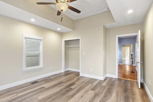a view of empty room with wooden floor and fan