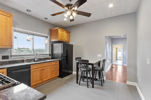 a kitchen with stainless steel appliances granite countertop a dining table chairs refrigerator and cabinets