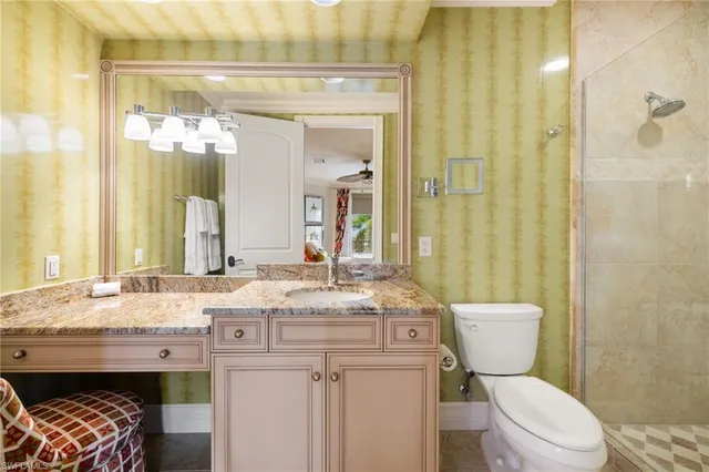 a bathroom with a granite countertop toilet a sink and a mirror