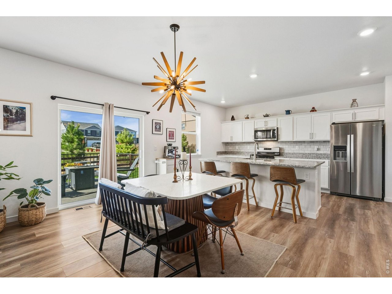 Open-concept dining and kitchen filled with natural light, center island, and contemporary lighting.