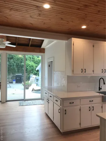 a kitchen with white cabinets and wooden floors