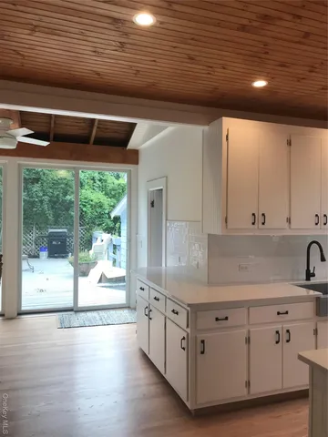 a kitchen with white cabinets and wooden floors