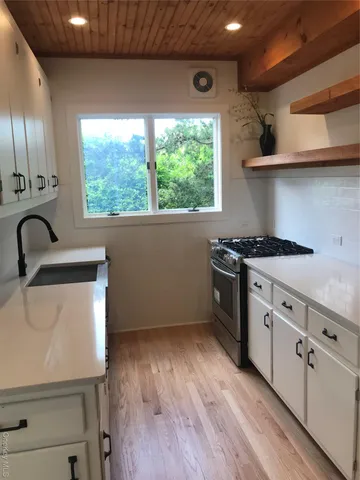 a kitchen with stainless steel appliances a sink a stove and a wooden floor