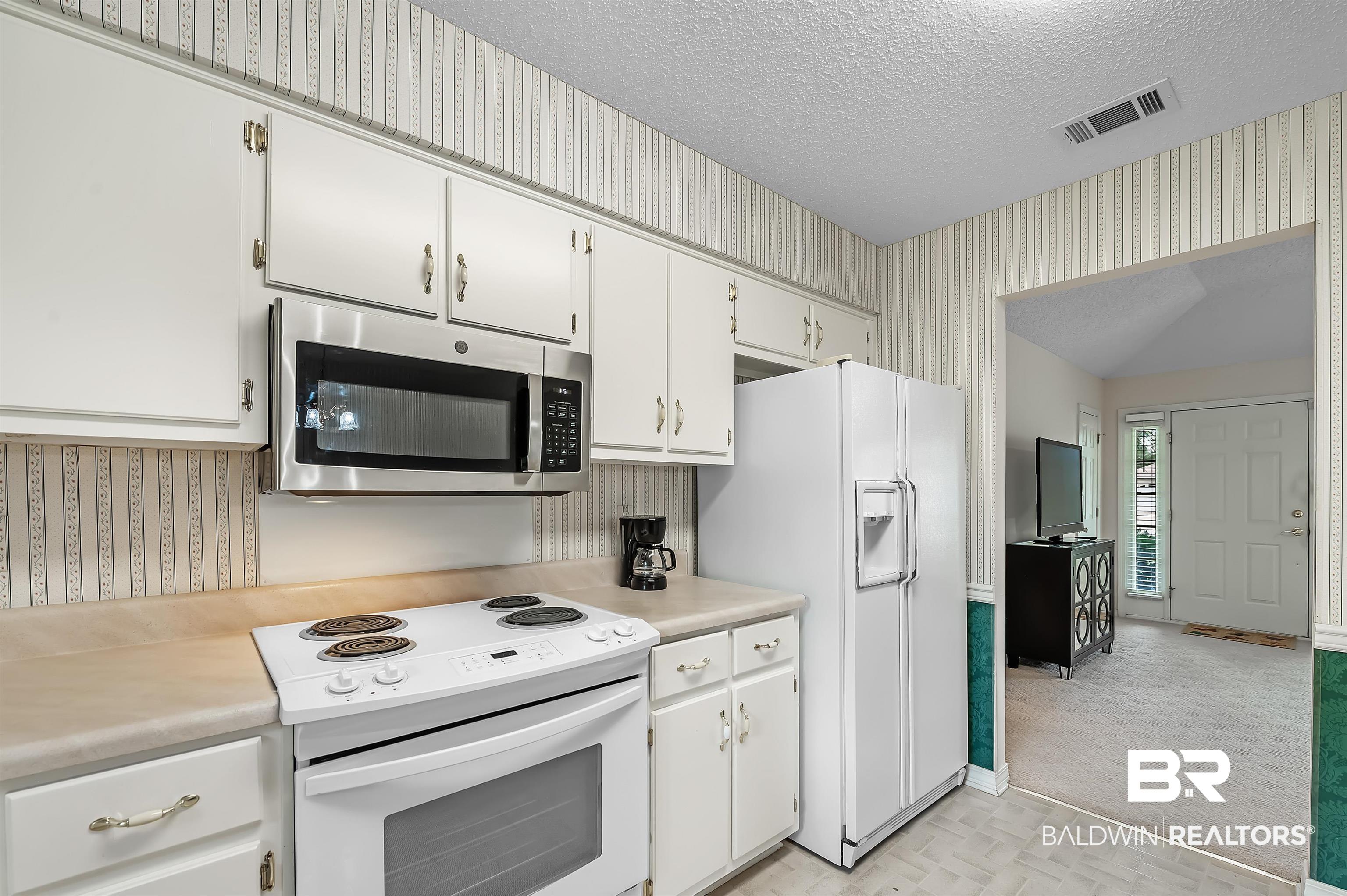 1502 Mulberry Lane Foley, AL 36535 - Photo 14 of 45 Kitchen with white cabinetry, light carpet, white appliances, and a textured ceiling