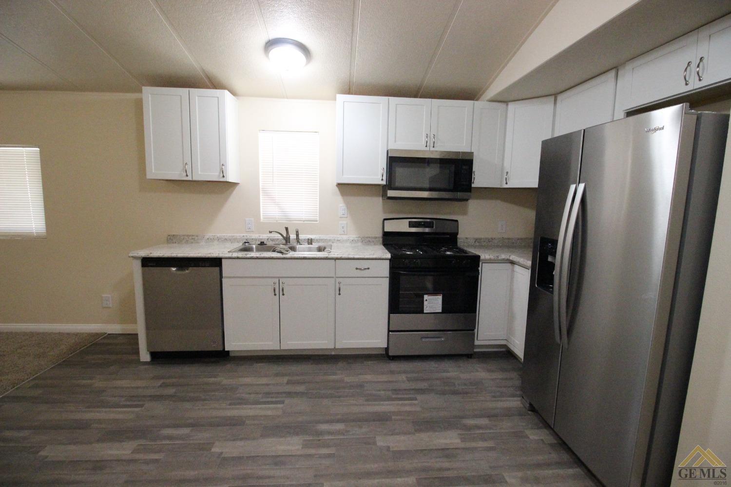 Undisclosed Address Bakersfield, CA 93308 - Photo 4 of 25 a kitchen with a sink a refrigerator and white cabinets