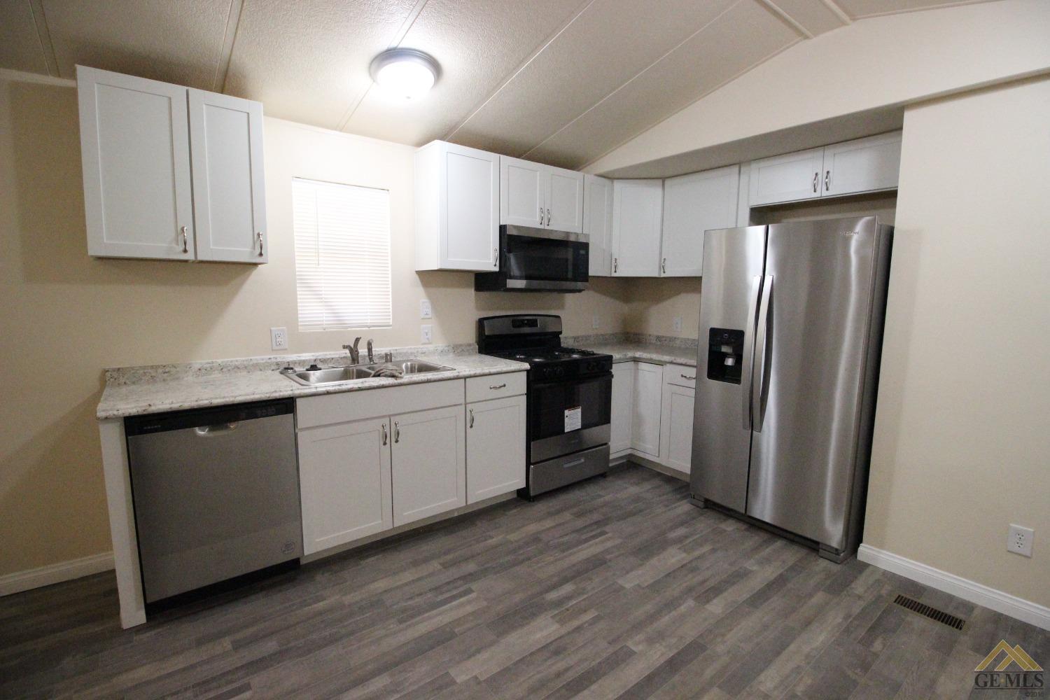 Undisclosed Address Bakersfield, CA 93308 - Photo 5 of 25 a kitchen with a sink a microwave a refrigerator and cabinets