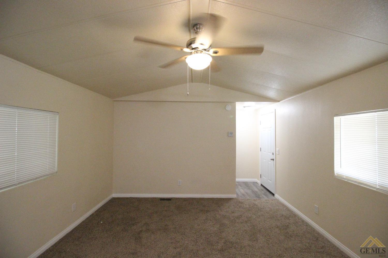 Undisclosed Address Bakersfield, CA 93308 - Photo 7 of 25 an empty room with a chandelier fan and windows