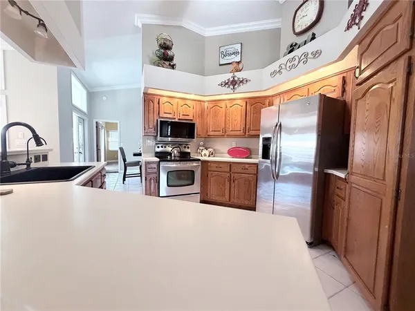 a kitchen with stainless steel appliances a refrigerator a sink a stove top oven a dining table and chairs