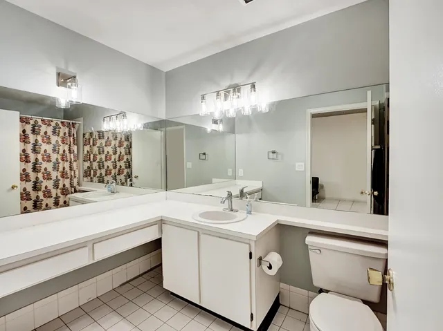 a bathroom with a sink a toilet and a large mirror