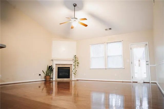 an empty room with wooden floor fireplace and windows