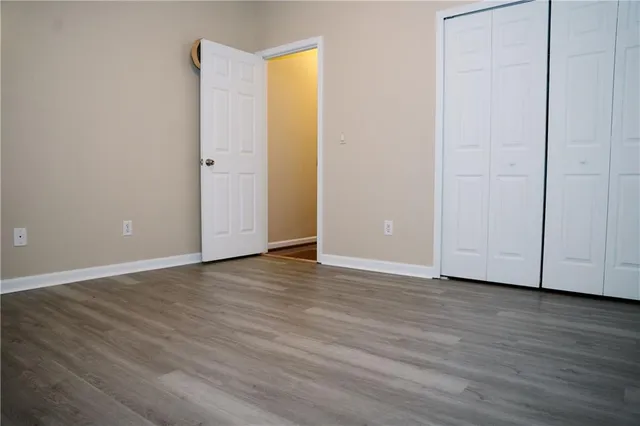 a view of an empty room with wooden floor and closet