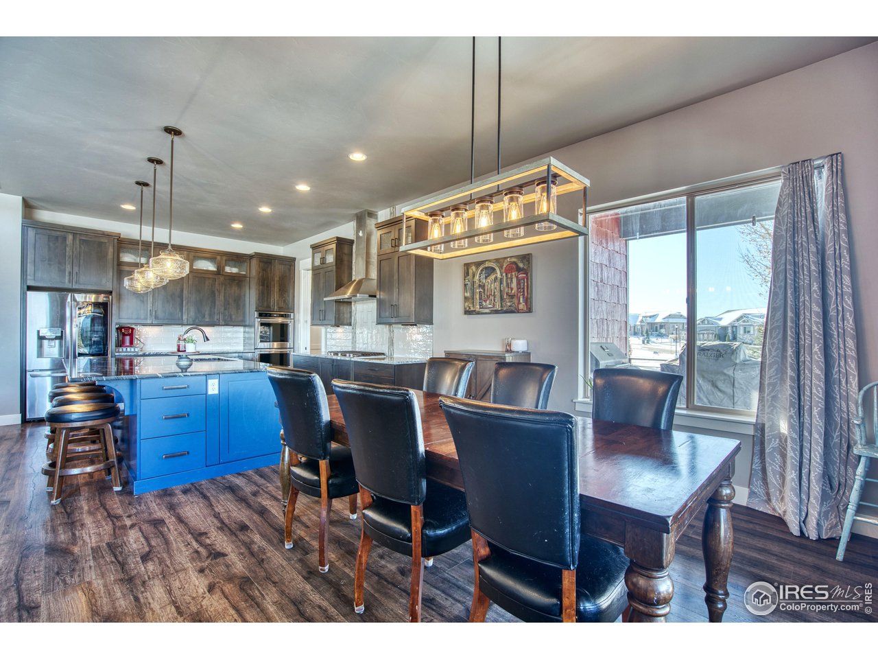 3941 Roper Trail Severance, CO 80524 - Photo 11 of 32 a kitchen with stainless steel appliances kitchen island granite countertop a table chairs and a view of living room