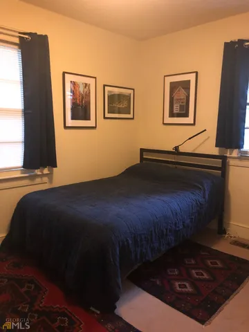 a bedroom with a bed dresser and window