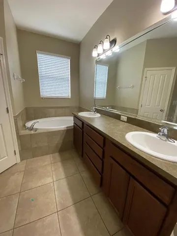 a bathroom with a granite countertop sink a toilet mirror and bathtub