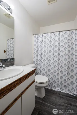 a bathroom with a granite countertop toilet a sink and a mirror