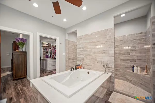 a large spacious bathroom with a tub sink shower and mirror
