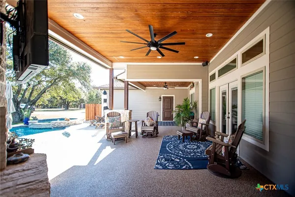 a view of a patio with table and chairs potted plants and floor to ceiling window