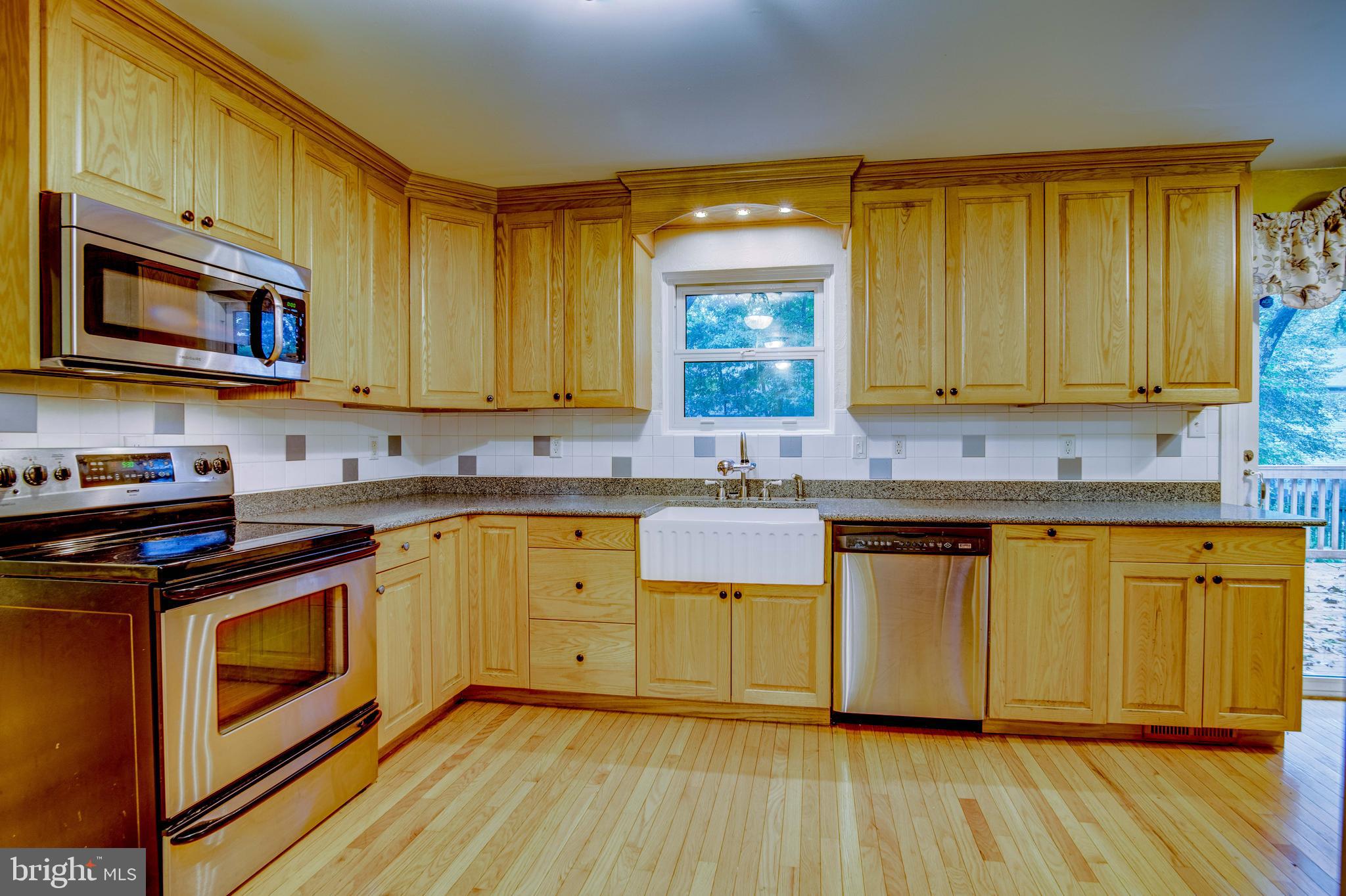 11431 Rawhide Road Lusby, MD 20657 - Photo 3 of 31 a kitchen with stainless steel appliances a stove a sink cabinets and a wooden floor