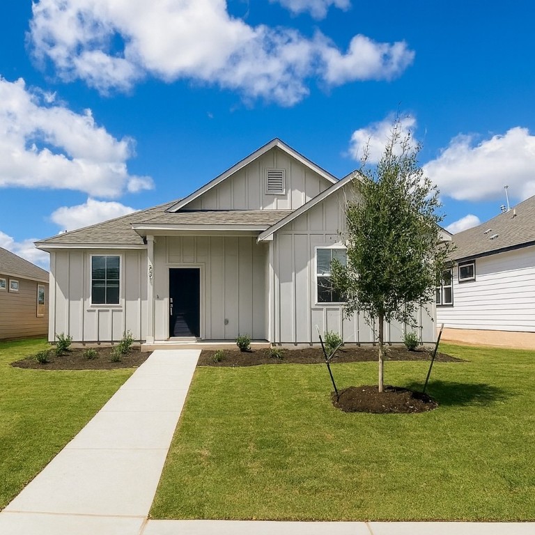 Single story home with board and batten siding, a shingled roof, a front yard, and a porch