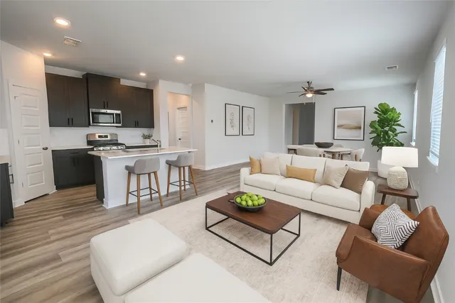 a living room with furniture kitchen view and a wooden floor