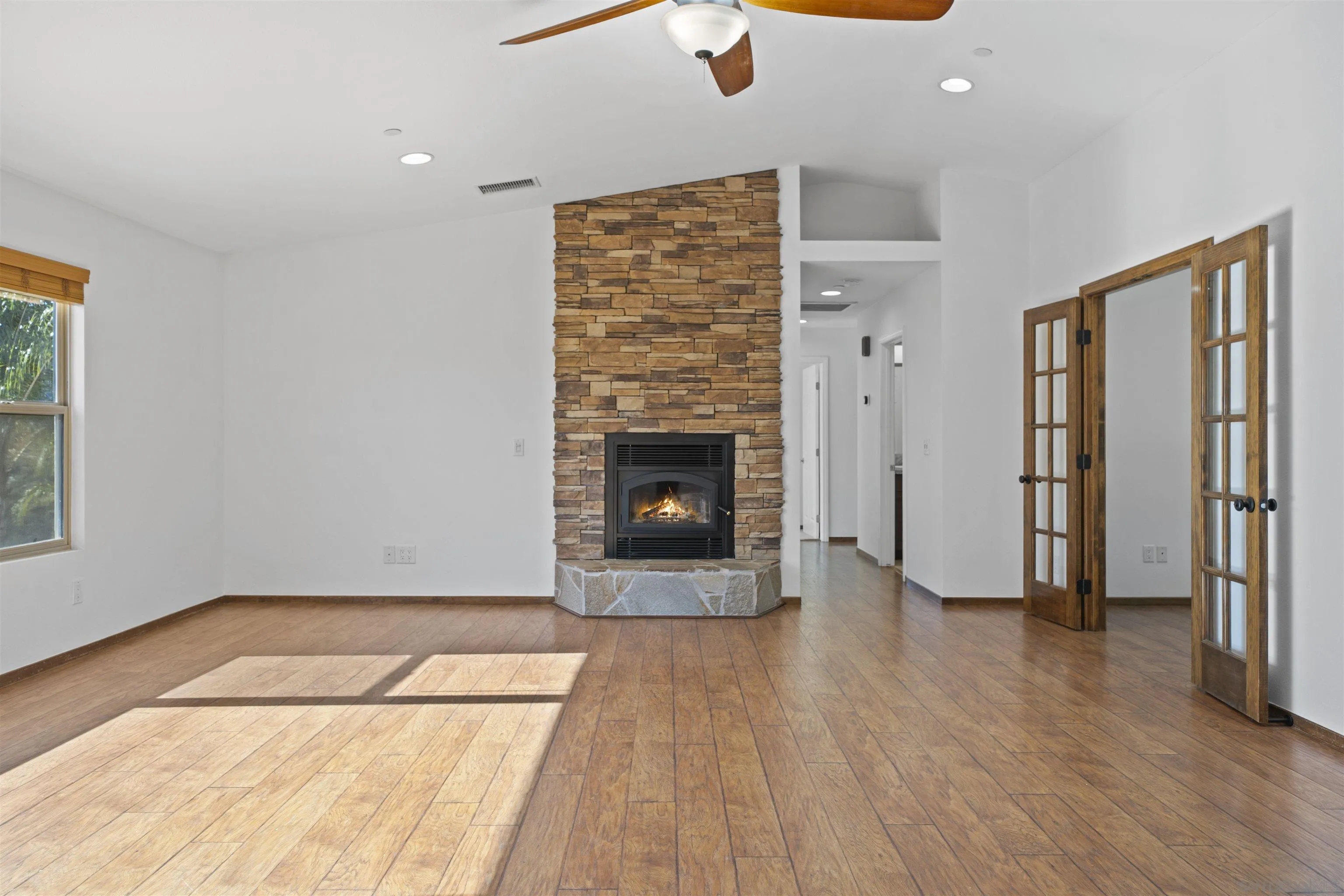 20872 Deerhorn Valley Road Jamul, CA 91935 - Photo 8 of 64 an empty room with wooden floor fireplace and windows