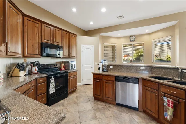 a kitchen with stainless steel appliances granite countertop wooden cabinets a stove a sink and a microwave