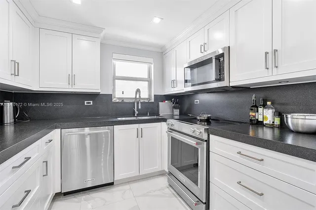 a kitchen with granite countertop white cabinets stainless steel appliances and sink