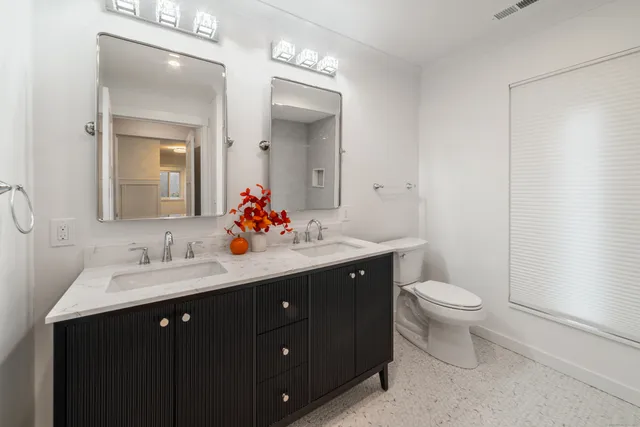 a bathroom with a double vanity sink toilet and mirror