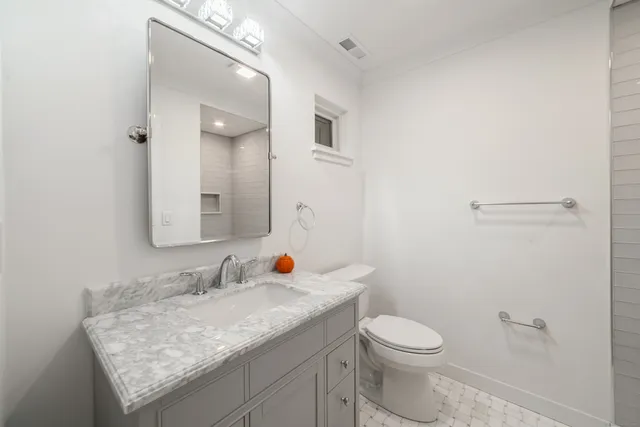 a bathroom with a granite countertop sink and a toilet