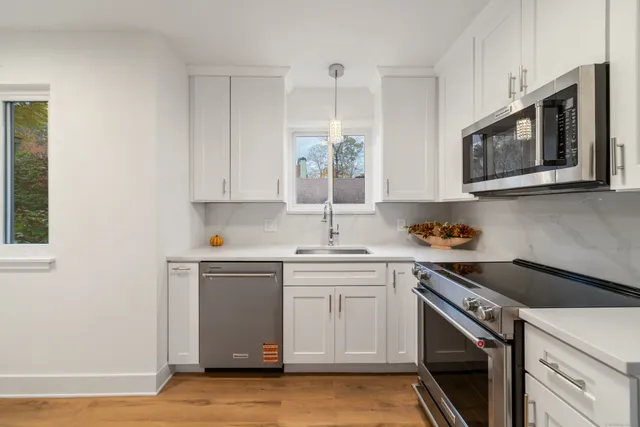 a kitchen with stainless steel appliances granite countertop a sink a stove a microwave and wooden cabinets