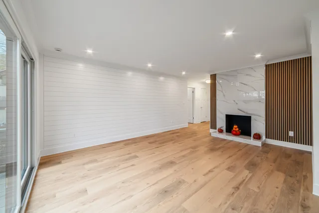 an empty room with wooden floor fireplace and windows