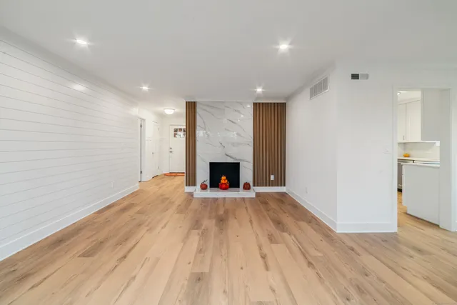 a view of an empty room with wooden floor fireplace and a window