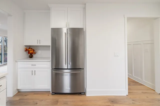 a view of a refrigerator in kitchen and white cabinets