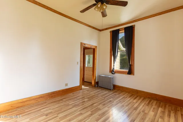a view of an empty room with a window and wooden floor
